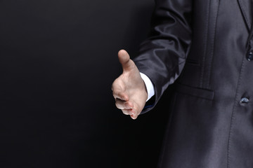 close up.businessman, hand out for a handshake.isolated on black background