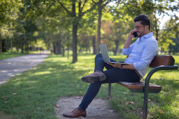 Fototapeta premium Handsome young businessman working on his laptop in the park