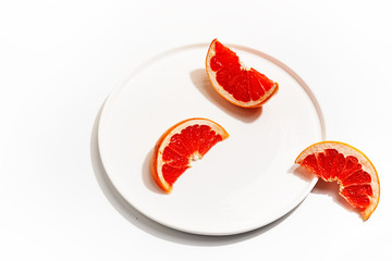 Slices of grapefruit on a white plate. Minimalistic concept. Top view.