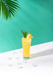iced pineapple punch cocktail in glass on green background. summer drink.