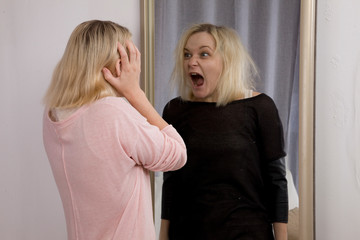 girl looks at herself in the mirror, sees himself in another reflection. The Dark Side, bipolar disorder, dissociative disorder