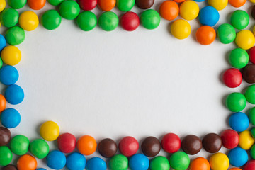 Fototapeta premium Colorful frame of multicolored candies on white background