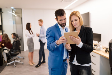 Businesspeople discussing while using digital tablet in office