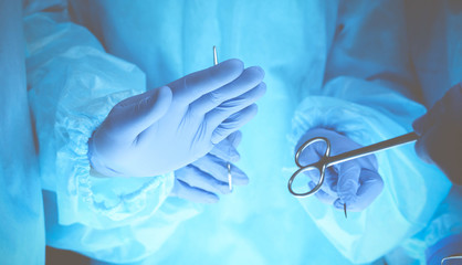 Surgeons hands holding surgical scissors and passing surgical equipment, close-up. Health care and veterinary concept