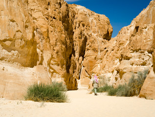 bedouin in white goes in the canyon in the desert among the rocks in Egypt Dahab South Sinai