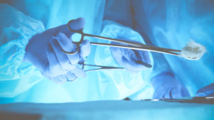 Surgeons hands holding surgical scissors and passing surgical equipment, close-up. Health care and veterinary concept