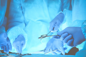 Surgeons hands holding surgical scissors and passing surgical equipment, close-up. Health care and veterinary concept