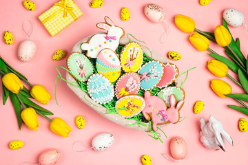 Easter homemade gingerbread cookies  in a basket on a pink background with tulips and easter...