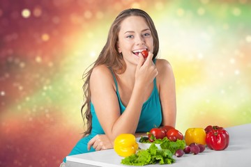 Young woman eating vegetables on blurred kitchen background