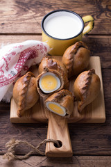 Russian traditional rye pies with egg, kokurki, on a wooden table