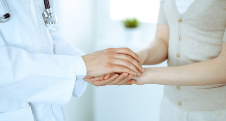 Fototapeta premium Hand of doctor reassuring her female patient. Medicine and health care concept