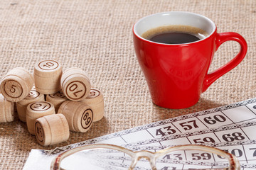 Board game lotto on sackcloth. Wooden lotto barrels and game cards with cup of coffee.