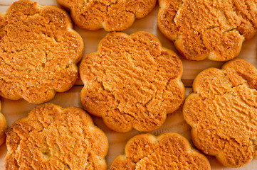 Tasty and beautiful cornflakes cookies among of corn flakes on a wooden table as background, top view