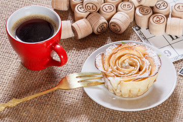 Board game lotto on sackcloth. Wooden lotto barrels and game cards with cup of coffee and homemade cookie on plate.