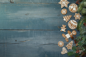 Christmas gingerbread on a blue wooden table decorated with branches of spruce. A Symbol Of Christmas. Festive food. The gingerbread man. Table decoration for the holiday. Christmas card. Empty space