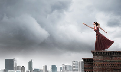 Blind woman in long red dress at top of building. Mixed media