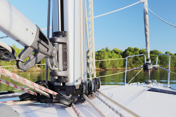 The mainmast is a mast and a twirled staysail on a sailing yacht and bow rails against the backdrop...
