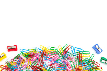 A lot of colored paper clips and pencil sharpeners on a white background. Top view and copy space.