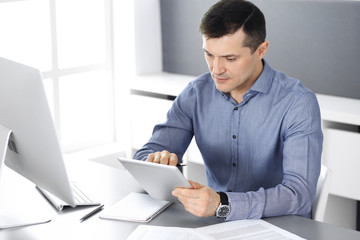 Businessman working with computer in modern office. Headshot of male entrepreneur or company director at workplace. Business concept