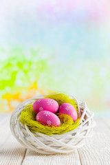 Easter eggs in the nest and wooden table on abstract background