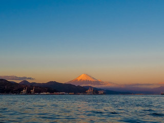 Naklejka na ściany i meble Mt. Fuji on Dream Ferry Mini Cruise traveling from Hamanako Lake, Shizuoka, Japan with sunset sky and industry plant background.
