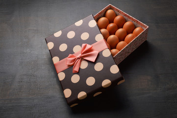 Raw eggs in a semi open gift box on black background