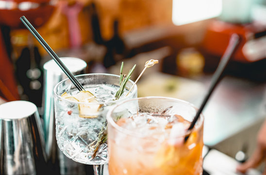 Cocktails Served On Bar Counter Prepared With Gin, Rosemary, Paper And Orange Juice - Drink, Nightlife, Lifestyle Concept - Focus On Top Crystal Glass