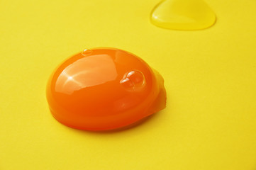 Raw egg yolk on the yellow background