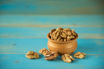 Walnuts on blue rustic table in wooden bowl