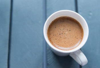 white mug with black coffee on grey background, top view