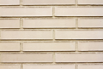 Slim yellow bricks on a cream or off-white brick wall as a background