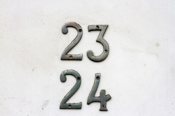 House number 23 and 24 with the twenty-three and twenty-four in silver on a white but dirty door