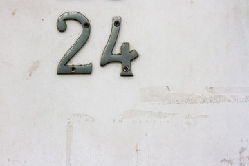 House number 24 with the twenty-four in silver on a white but dirty door