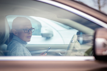 Pretty, young woman driving her new car - putting the necessary parking clock behind the...