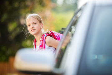 Cute little girl going home from school, looking well before crossing the street, trying not to get...