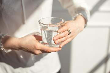 Female hands holding a transparent glass of water. Healthy lifestyle.