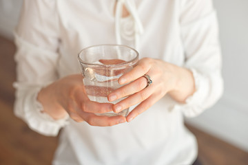 Female hands holding a clear glass of water.A glass of clean mineral water in hands, healthy drink