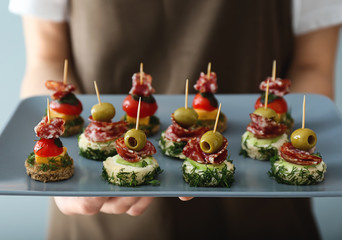 Chef holding plate with tasty canapes, closeup