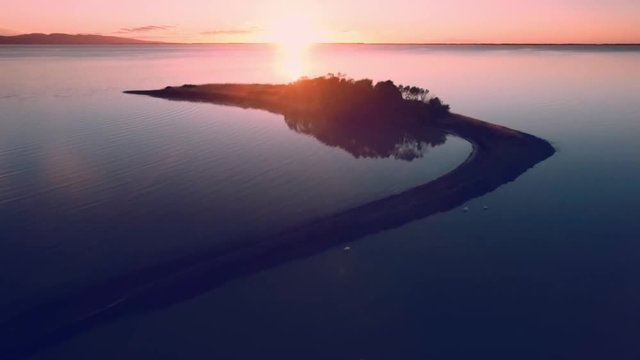 Aerial footage of sunrise above tranquil Lake Ellesmere near Christchurch, New Zealand