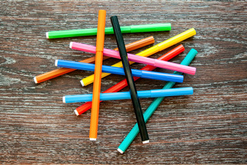 Several markers lie on the surface, top view. Felt pens lie in a heap randomly.