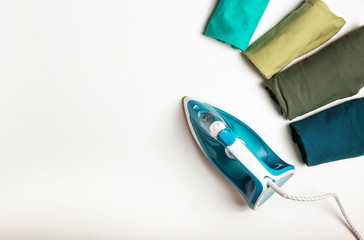 Iron with clean clothes on white background