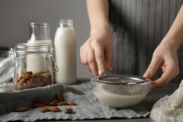 Woman making healthy almond milk in kitchen