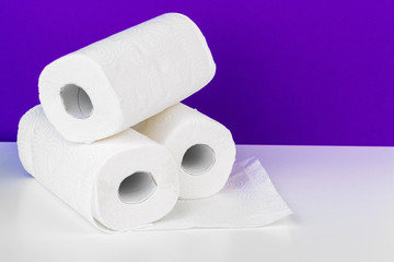 Roll of paper towel on table against purple background