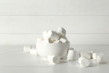Bowl with tasty marshmallows on white wooden table