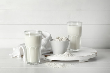 Obraz na płótnie Canvas Glasses of milk with flour in bowl on white wooden background