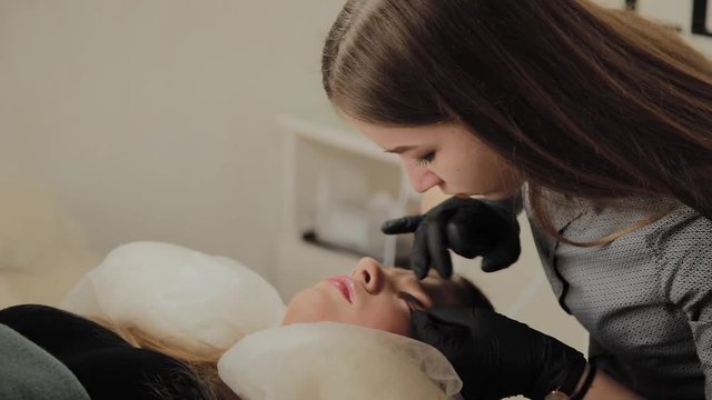 A very beautiful girl in a beauty salon does a lamination lashes. Beautician performs the procedure eyelash fragmentation.