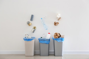 Garbage falling into trash bins near white wall
