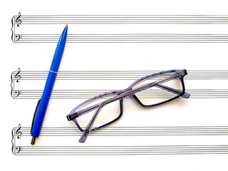 Blank music staff with with ten staves, treble and bass clefs and glasses and pen on it. Clean...