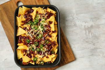 Baking dish with tasty nachos, minced meat and chili on grey table