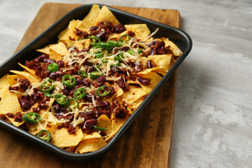 Baking dish with tasty nachos, minced meat and chili on grey table